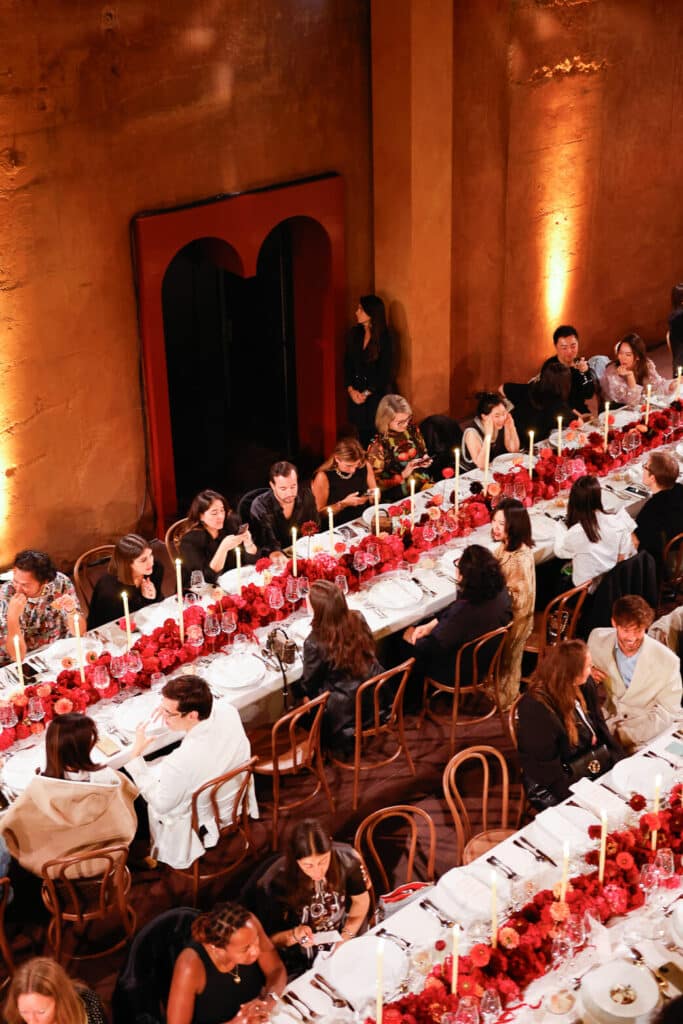 Editorial event photography of a Louis Vuitton dinner at La Fábrica de Ricardo Bofill, featuring an elegant long-table setting with red floral arrangements and candlelight. Photo by Santa Cruz Juanjo Vega, photographer of exclusive events and luxury brands